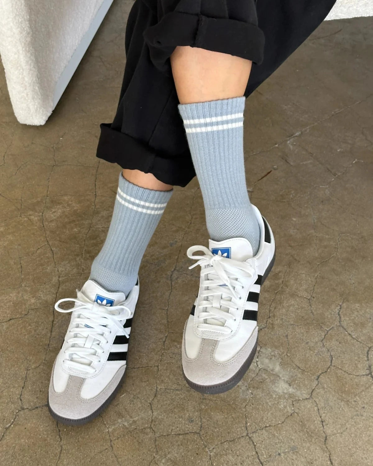 Person wearing gray socks with white sneakers on a concrete floor