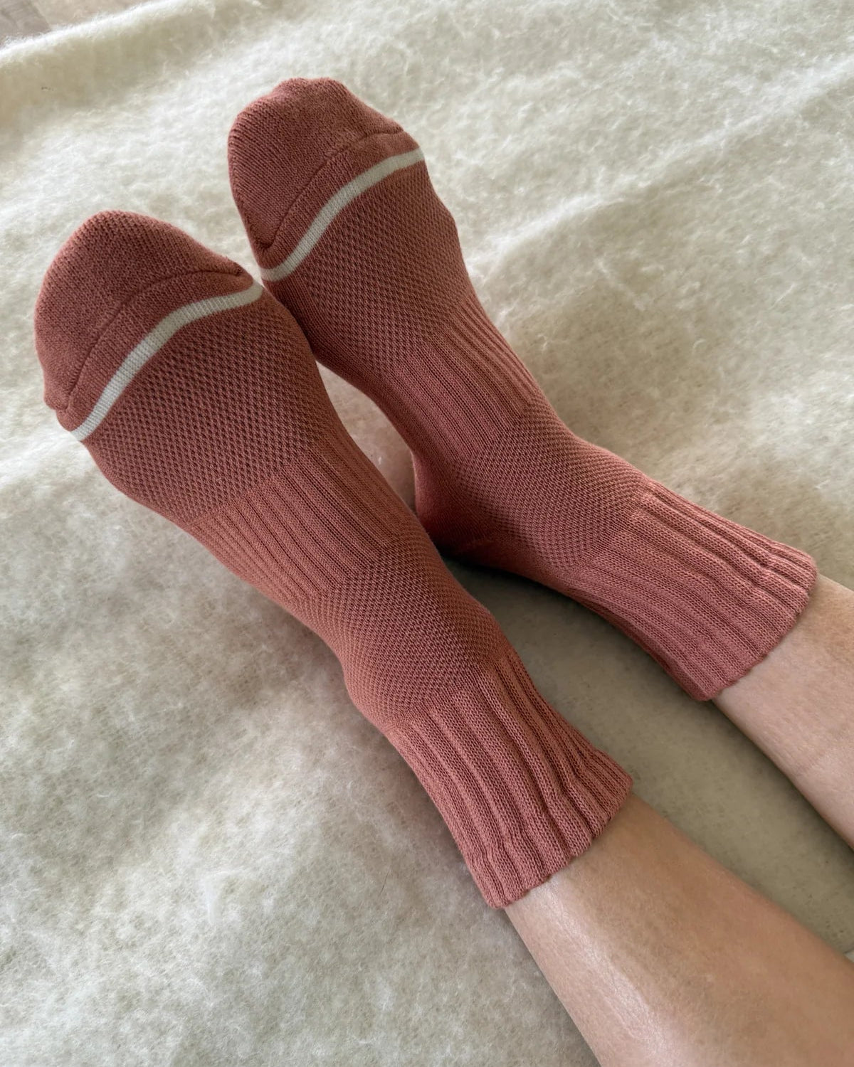Pair of pink socks with white trim on a light background