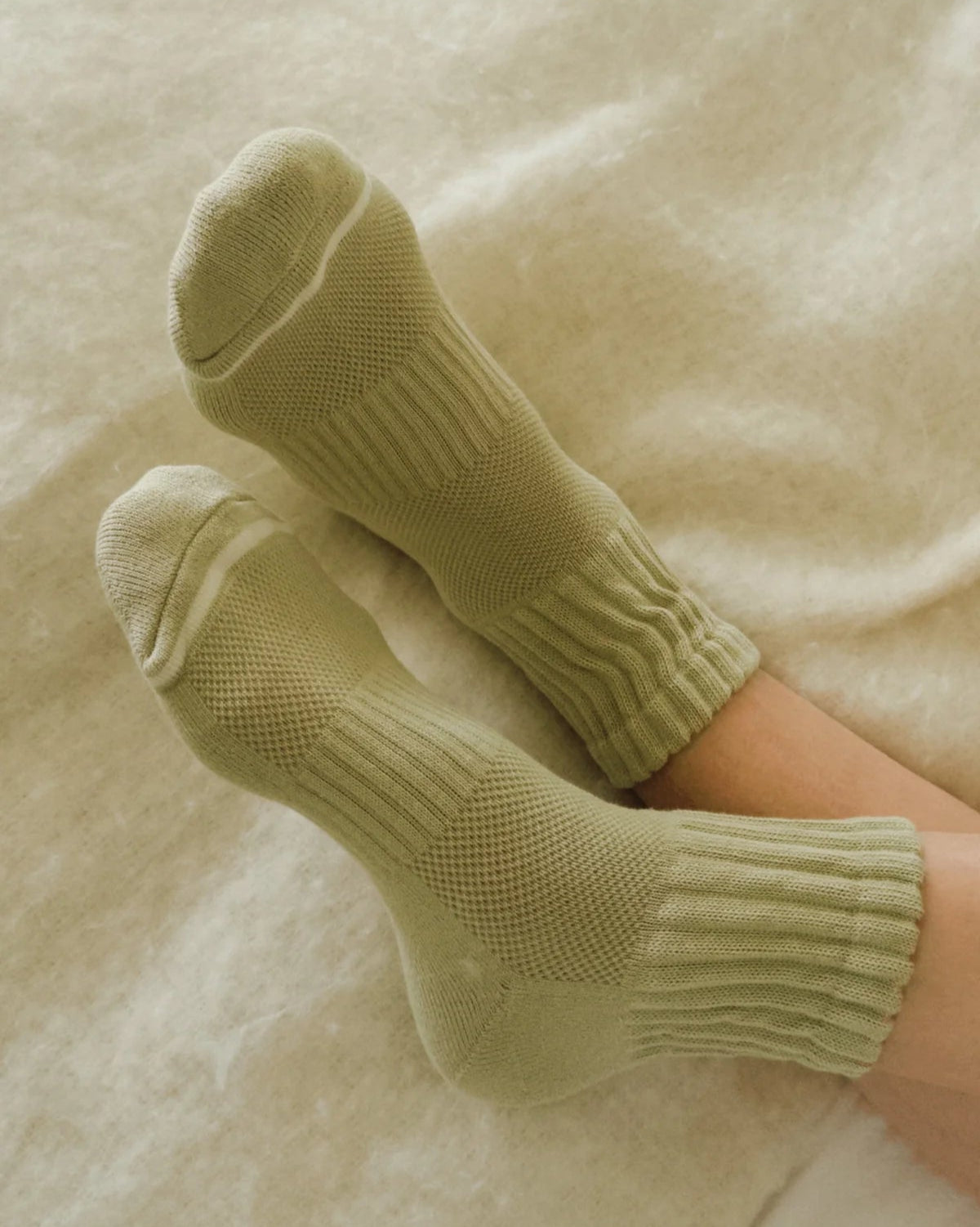 Green socks on a soft beige blanket