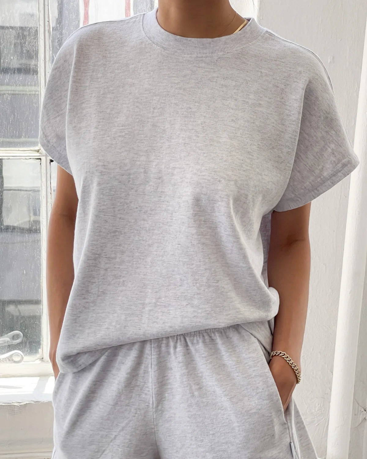 Person wearing a gray t-shirt and shorts set indoors.